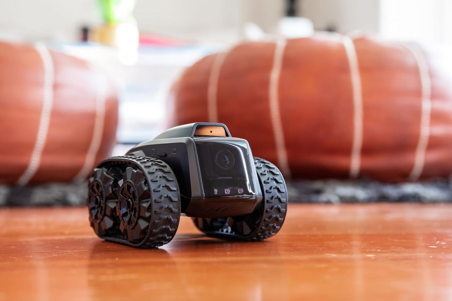 All-terrain mobile camera robot with grippy tires on wooden floor ready for monitoring spaces.