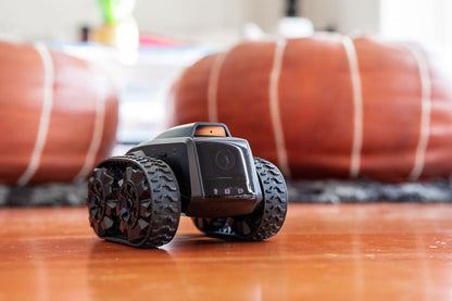 All-terrain mobile camera robot with grippy tires on wooden floor ready for monitoring spaces.